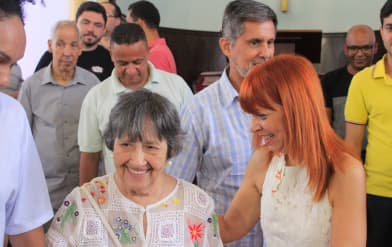Uma senhora ao lado de uma jovem ruiva sorrindo enquanto participa do culto
