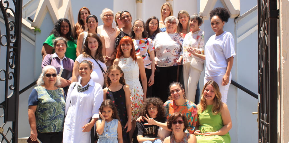 Grupo de mulheres sorrindo em uma escadaria em frente a igreja